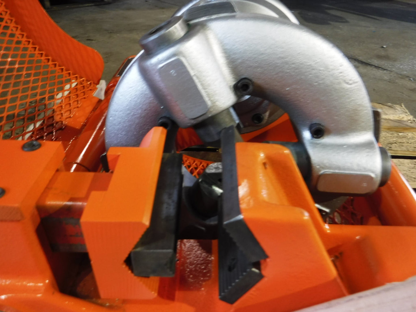 A close-up of the Aeroquip FT1013-1-5 Reusable Hose Assembly Machine (Reconditioned) shows an orange vise holding a pipe and a quick acting wrench chuck, with a silver threading die head in a busy workshop.