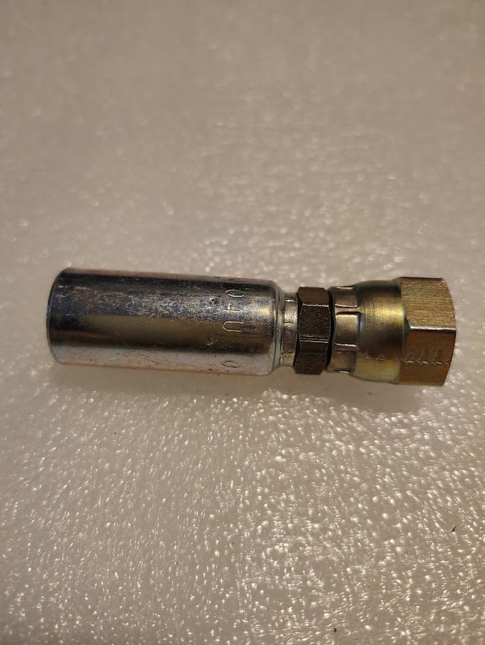 A close-up of the 04U-04L Weatherhead 1/4 Hose x 1/4 JIS Female Fitting (CS40-4X4) with a shiny cylindrical end and hexagonal brass nut, on a textured white surface—designed for versatile Weatherhead applications.