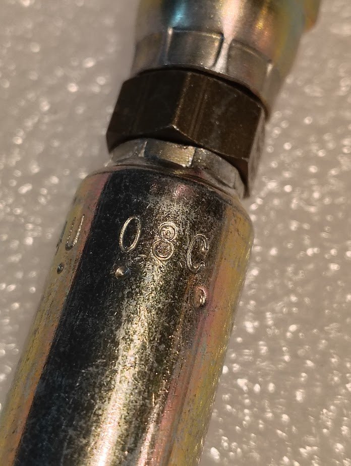 Close-up of a 04U-08C Weatherhead 1/4 Hose x M14x1.5 DIN Female Fitting (CS37-4X8), a metallic cylindrical part with 08C stamped on it, shown against white foam or bubble wrap in the background.