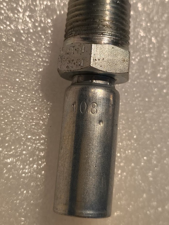 A close-up photo of the 04U-108 Weatherhead 1/4” Hose x 1/2” NPTF Male Fitting (CS01-4X8), designed for hydraulic hose systems, showing “108” engraved on its metallic body atop a textured white surface.