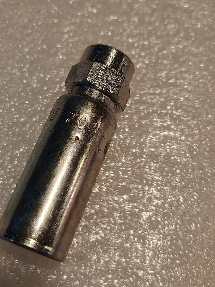 A close-up image shows the 04U-202 Weatherhead 1/4 Hose x 1/8 NPTF Female Fitting on a textured, bubble-like surface. The fitting features engraved numbers and a hexagonal end, making it suitable for tightening or loosening nuts and bolts.