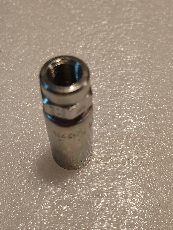 A shiny 04U-202 Weatherhead 1/4 Hose x 1/8 NPTF Female Fitting (CS02-4X2) with a hexagonal opening stands upright on a textured white surface, resembling those used for hydraulic hose fittings.