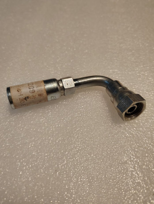 A Weatherhead 04U-60D 1/4 hose x M16x1.5 DIN female hydraulic fitting with a 90-degree bend rests on a textured, light surface; one end has a hex nut, the other has a marked cylindrical crimp sleeve.