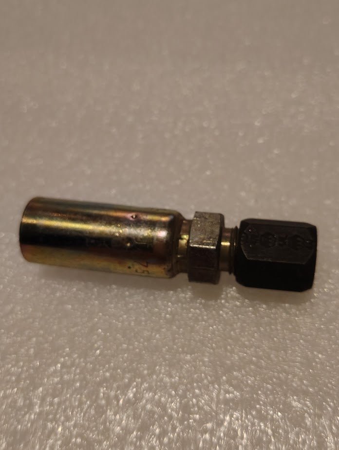 A close-up of the Weatherhead 04U-755, a 1/4 hose x 5/16 compression fitting (CS28-4X5), featuring a brass-colored cylindrical body with a black hex connector, commonly used in hydraulic setups on a textured white surface.