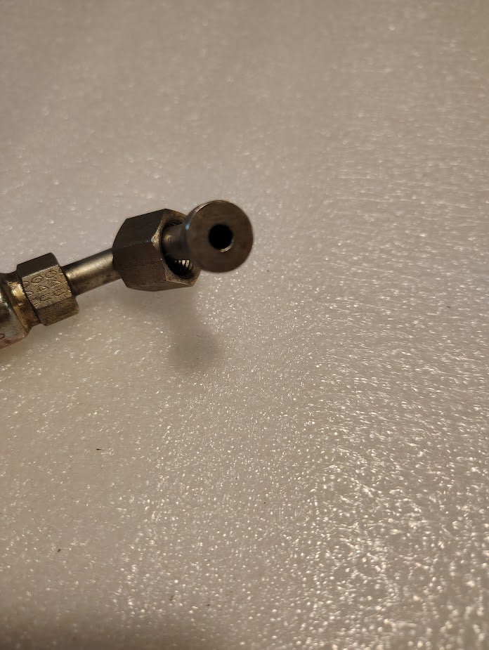 Close-up of the Weatherhead 04U-A64 (1/4 Hose x 1/4 ORF Female Fitting, CS33-4X4) with hexagonal nut, used for hydraulic hoses, resting on a textured white surface. The circular opening faces the camera.