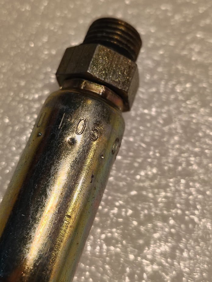 A close-up of the 04U-P05 Weatherhead 1/4 Hose x 5/16 ORB Male Fitting (CS11-4X5), a metallic cylinder with hex nut and P05 engraving, commonly used in hydraulic hose fittings, lies on a textured white background.