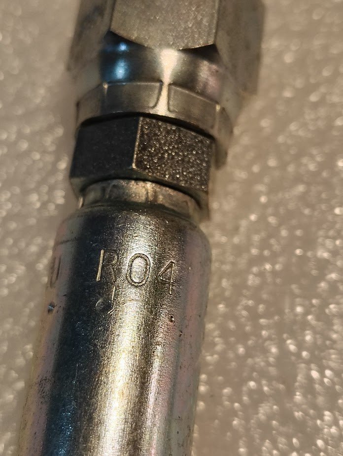 Close-up of a Weatherhead 04U-R04 1/4 Hose x 1/4 ORB Male Fitting (CS12-4X4), featuring R04 engraving, placed on a textured white background.