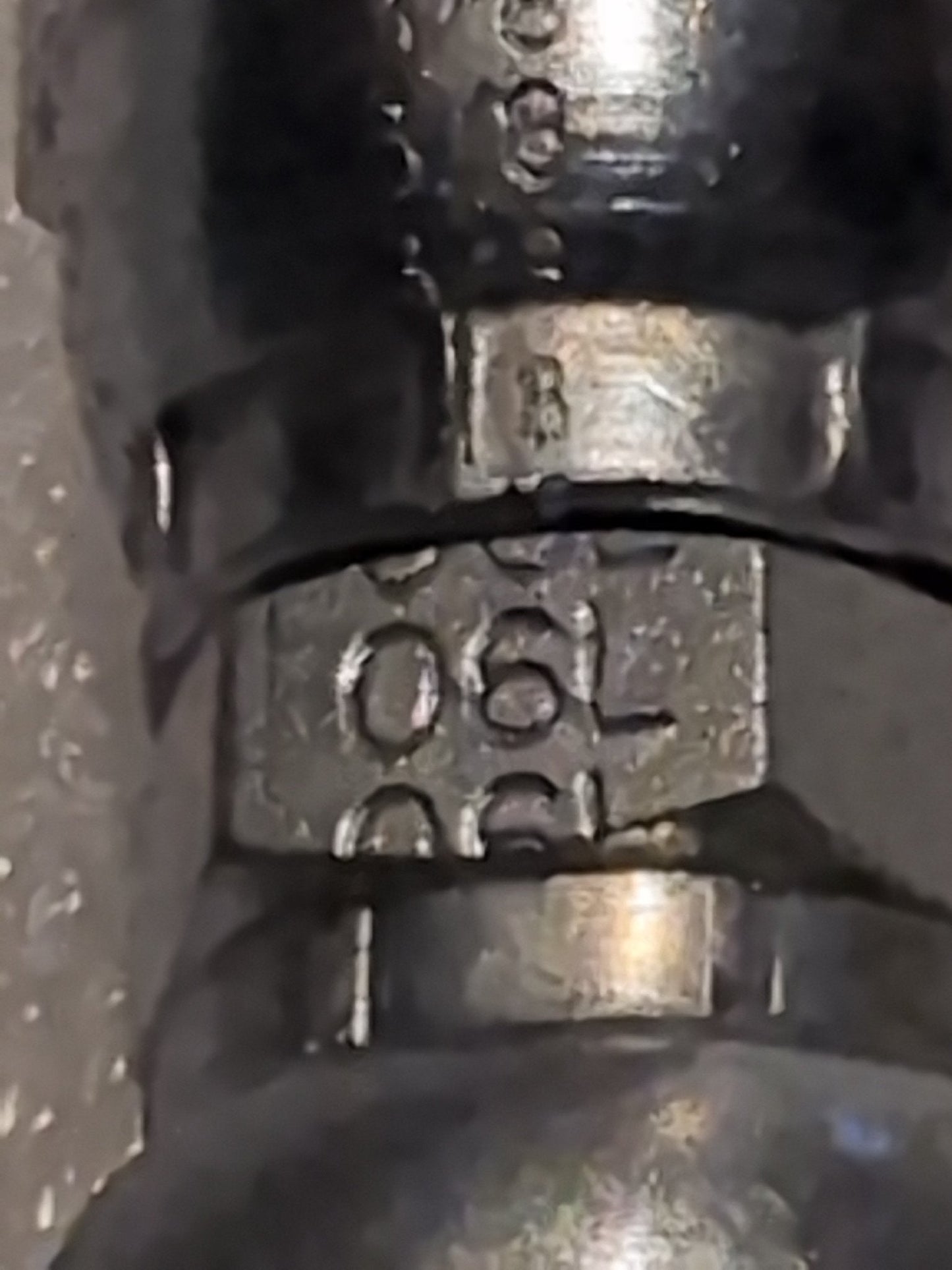 Close-up of a Weatherhead 06U-06L 3/8 Hose x 3/8 JIS Female Fitting (CS40-6X6), its metallic, slightly worn surface engraved with markings, designed for compatibility with hydraulic hose fittings.