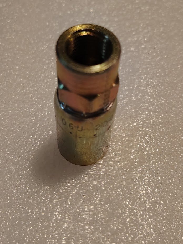 A Weatherhead 06U-204 3/8 hose x 1/4 NPTF female fitting (CS02-6X4) stands upright on a textured white surface, with threading visible at the top and faint markings on the side.