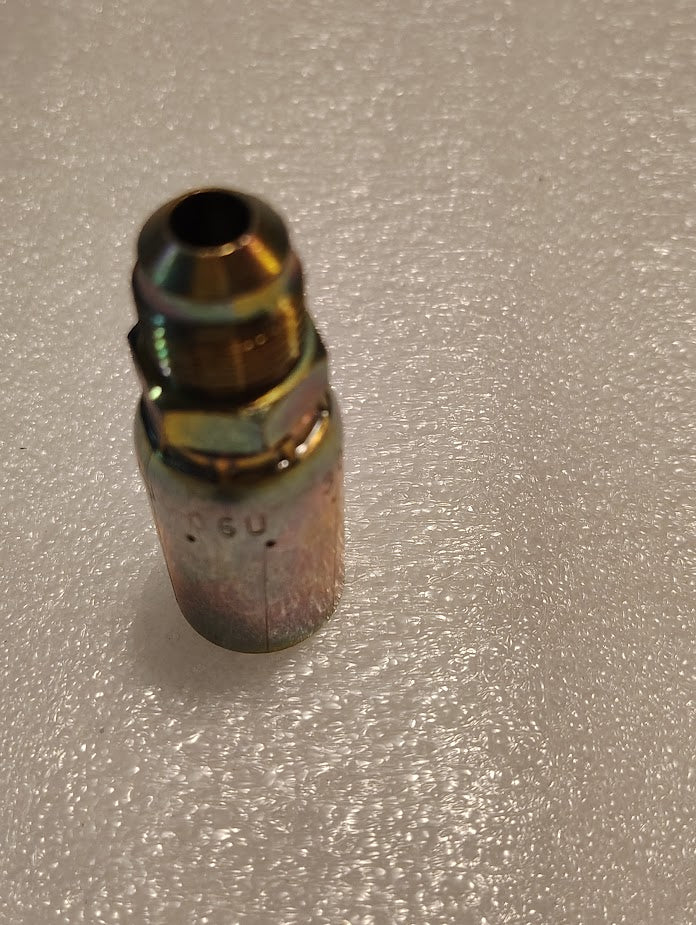 The Weatherhead 06U-306 CS06-6X6 is a shiny, cylindrical 3/8 hose x 3/8 SAE male fitting with a reflective finish. It stands upright on a textured white surface, showing its threaded end, and fits 100R1 hydraulic systems.