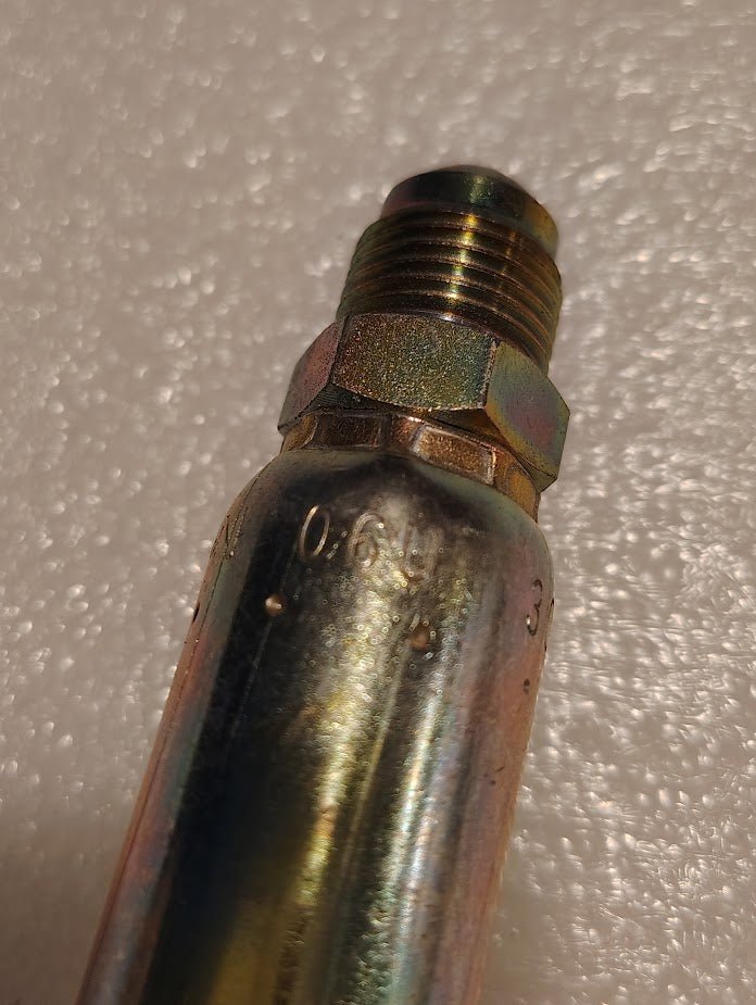 Close-up of a Weatherhead 06U-306, a 3/8 hose x 3/8 SAE male fitting (CS06-6X6), with engraved markings on a textured white surface that resembles foam or bubble wrap.