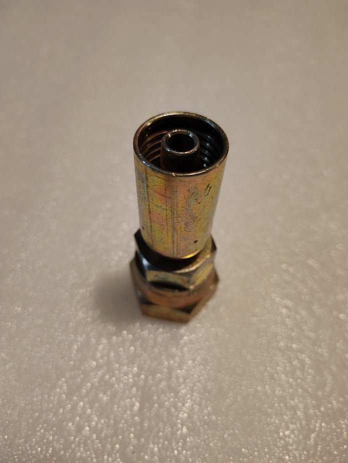 A close-up of the 06U-612 | Weatherhead 3/8 Hose x 3/4 JIC Female Fitting (CS09-6X12) with threaded interior, upright on a textured white surface; compatible with Parker hydraulic hose and Weatherhead fittings.