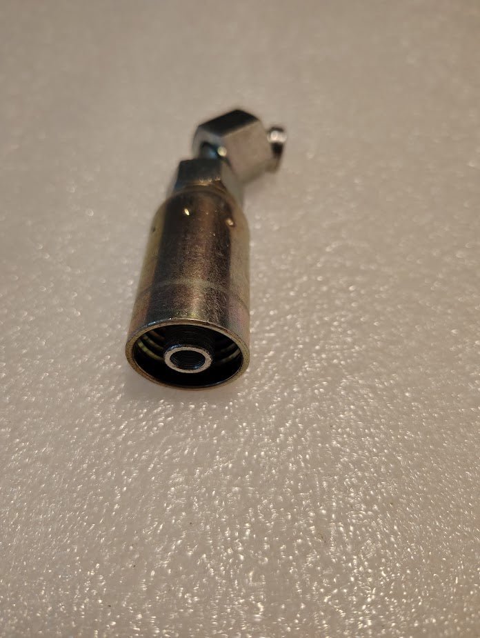 Close-up of a metallic cylindrical tool resembling the Weatherhead 3/8 Hose x 1/4 ORF Female Fitting - 90 Short Swivel, with a small side attachment on a textured surface.