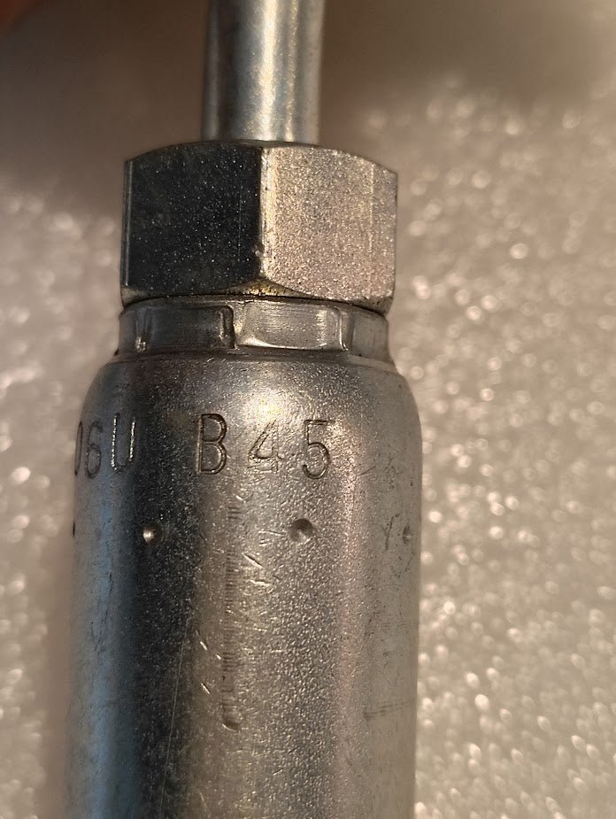 Close-up of a Weatherhead 06U-B45, a 3/8 hose x 5/16 inverted male fitting (CS19-6X5), showing engraved B45 and 06U markings, hexagonal nut, and textured background—ideal for hydraulic hose fittings.