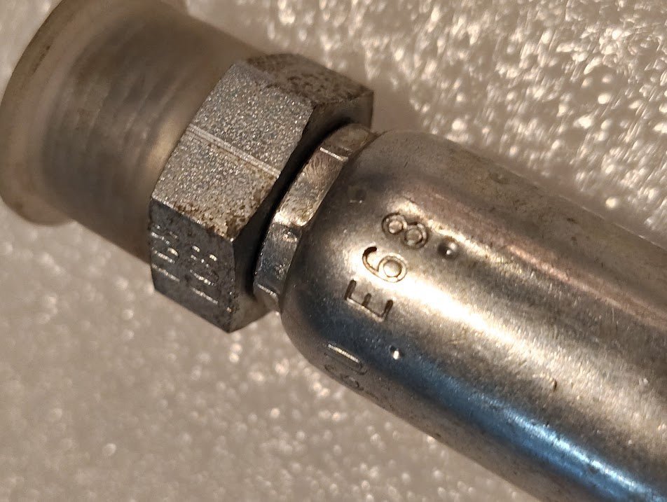Close-up of a 06U-E68 | Weatherhead 3/8 Hose x 1/2 ORF Male Fitting (CS29-6X8), featuring a hexagonal nut and number markings, against a textured white background—compatible with hydraulic hose fittings.