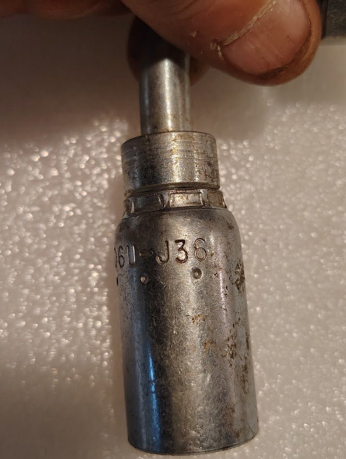 A close-up of a hand holding a Weatherhead 06U-J36, a 3/8 hose x 3/8 ORF female fitting (CS34-6X6), shows visible wear and rust against a white background; commonly used in hydraulic hose systems.