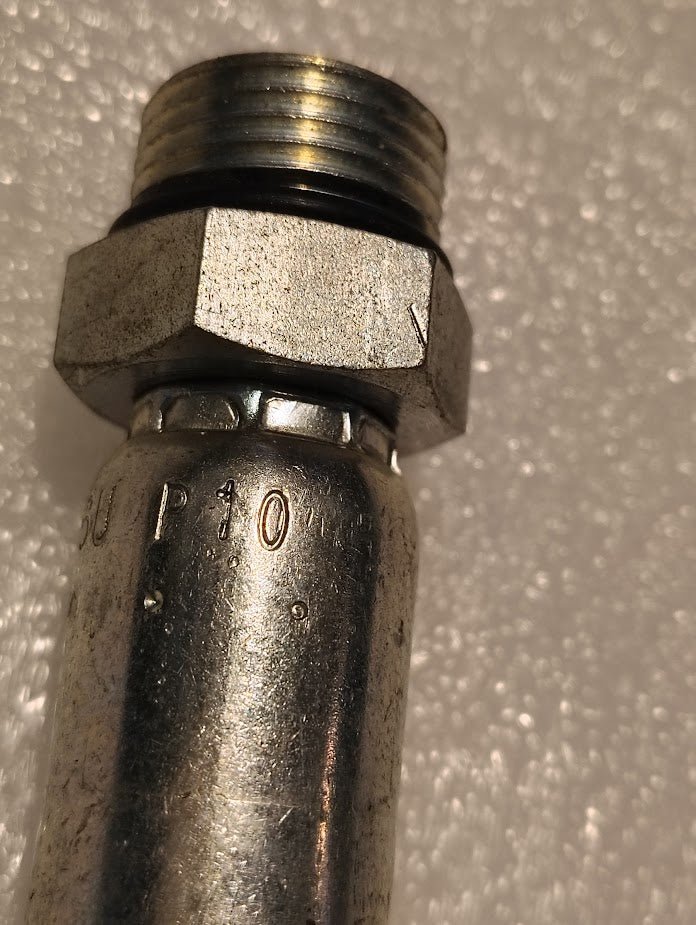 Close-up of a 06U-P10 Weatherhead 3/8 Hose x 5/8 ORB Male Fitting (CS11-6X10) with hex nut and threaded end, compatible with 100R hoses and SUP 10 engraving, resting on a textured white surface.