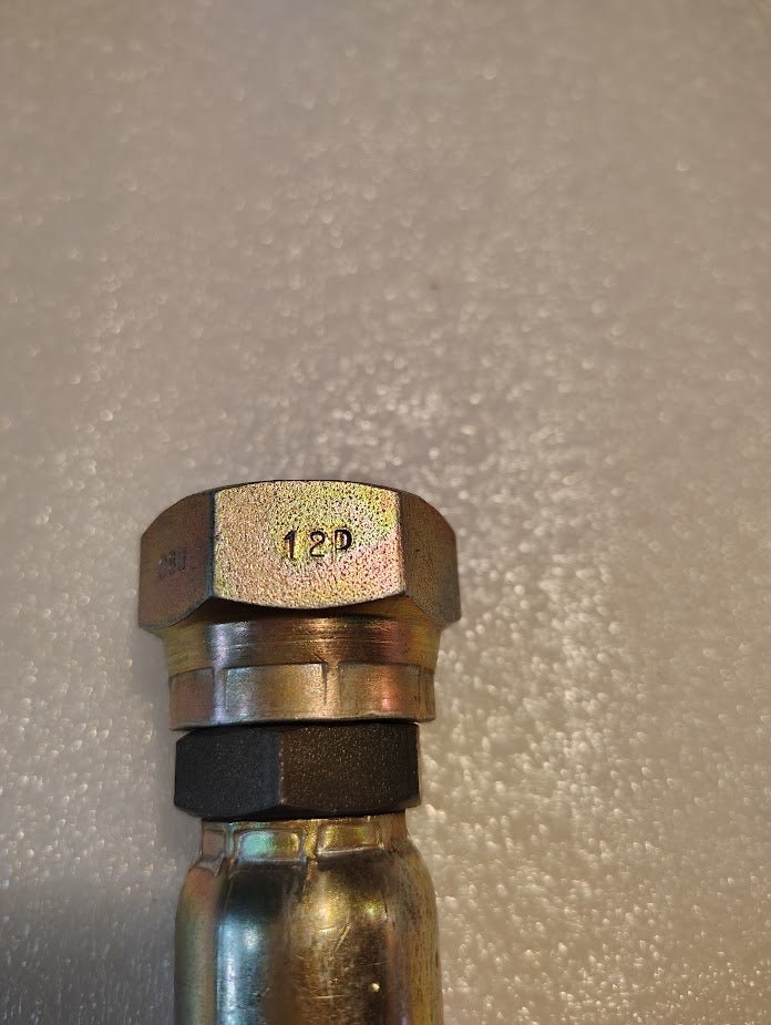 A close-up of a Weatherhead 08U-12P 1/2 Hose x 3/4 BSPP Swivel Fitting—Straight, attached to a metal pipe, with 18P stamped on top. The background features a textured, light-colored surface.