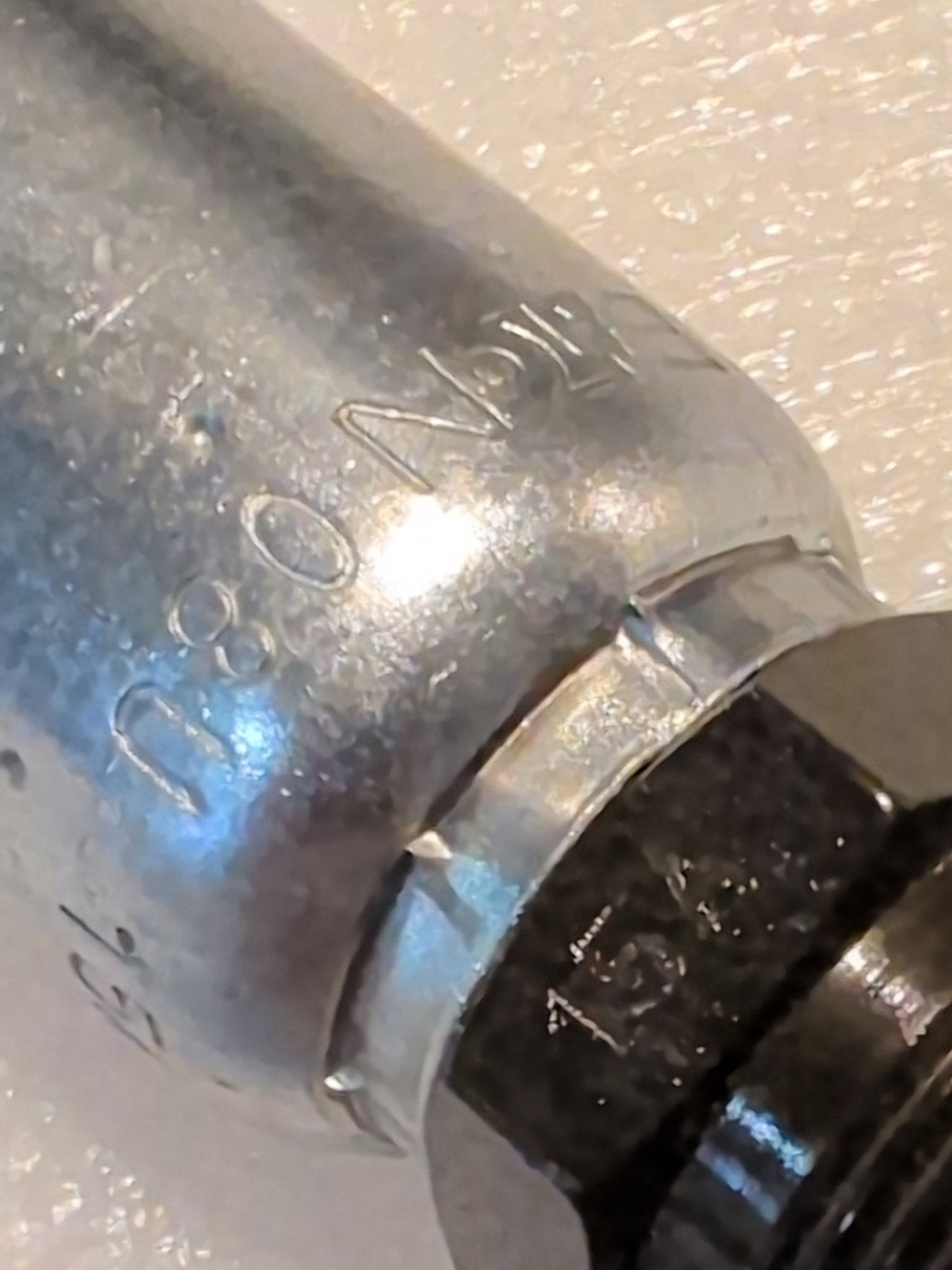 Close-up of a Weatherhead 08U-15A fitting (1/2 Hose x M22x1.5 DIN Male, CS66-8X15) with engraved markings. The metallic hydraulic fitting is shown against a textured, light-colored background.