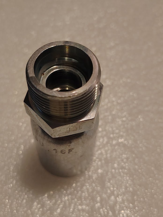 The Weatherhead 08U-16F (CS67-8X16) is a 1/2 hose x M24x1.5 DIN male hydraulic fitting with a hexagonal metal body, shown upright on a textured white surface.