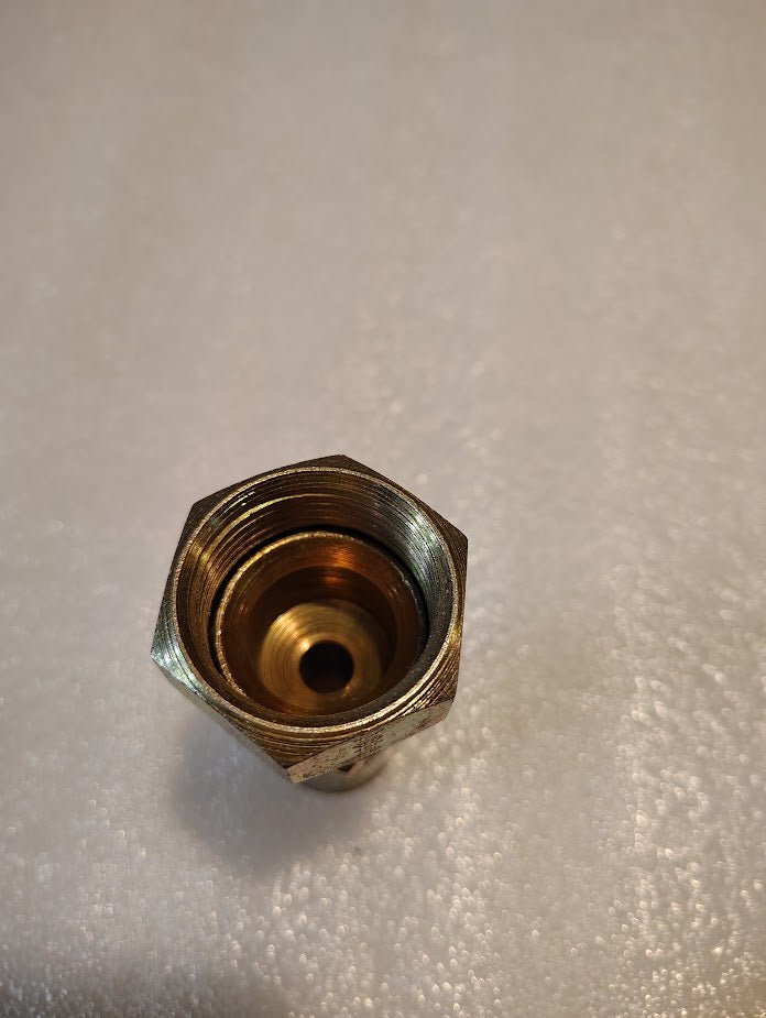A close-up of the Weatherhead 08U-616 fitting (1/2 hose x 1 JIC female), shown upright on a textured white surface, perfect as an interchangeable brass hexagonal connector in multiple applications.
