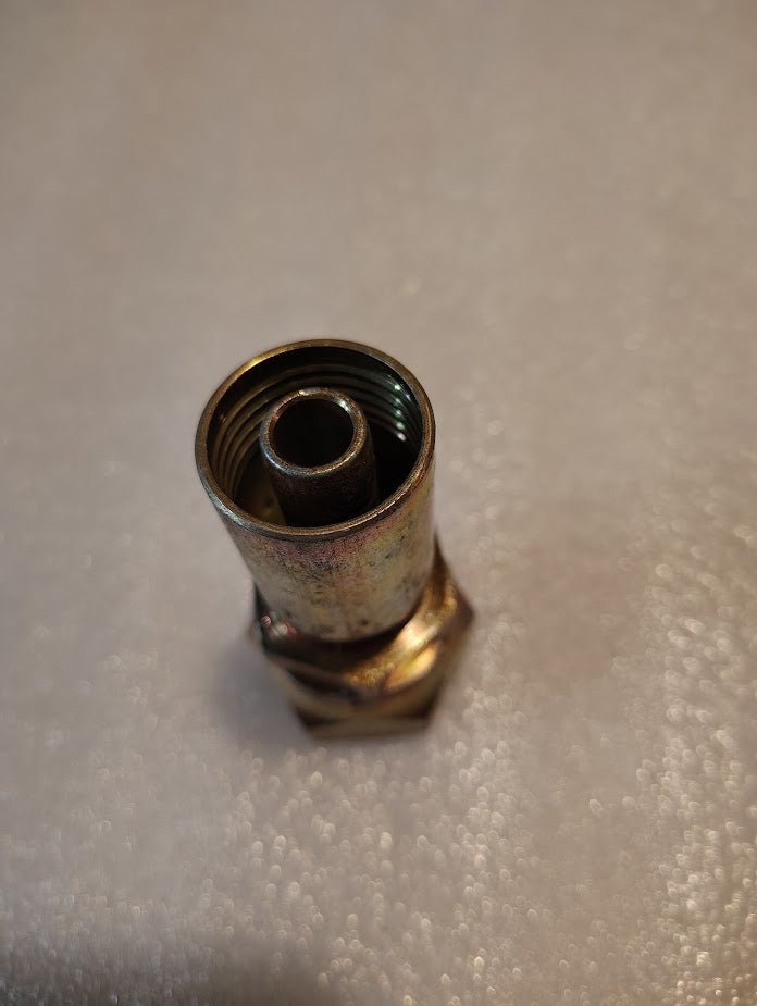 A close-up of the 08U-616 Weatherhead 1/2 Hose x 1 JIC Female Fitting (CS09-8X16) standing upright on a textured, light-colored surface.