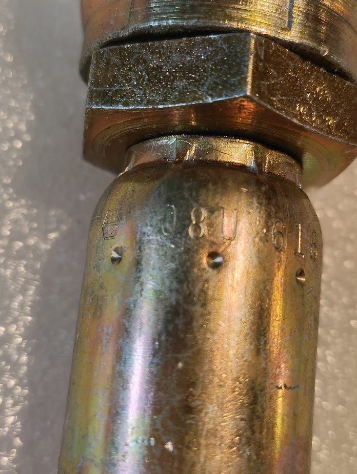 Close-up of a Weatherhead 08U-616 (CS09-8X16) 1/2 hose x 1 JIC female fitting, showing its metallic threaded joint and hexagonal nut with engraved markings, under bright reflective lighting.