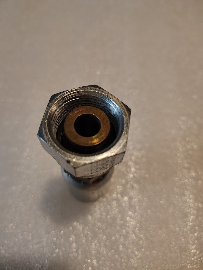 A close-up of the 08U-66C Weatherhead 1/2 Hose x M24x1.5 DIN Female Fitting (CS38-8X16) with brass insert, upright on a textured white surface—ideal for hydraulic or Weatherhead hose fittings.