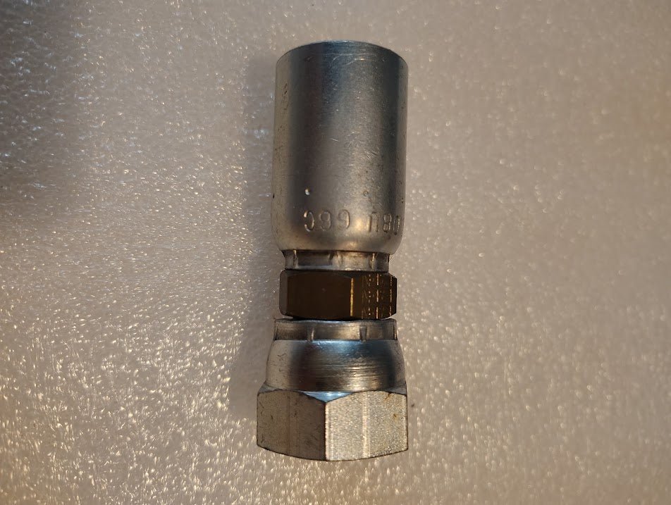 A close-up of the 08U-66C Weatherhead 1/2 Hose x M24x1.5 DIN Female Fitting (CS38-8X16) with a hex nut, shown on a textured, light surface.