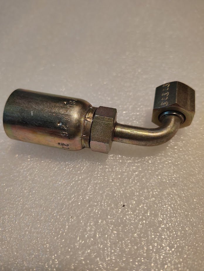 The 08U-A26 Weatherhead 1/2 Hose x 3/8 ORF Female Fitting (CS32-8X6), featuring a bent tube and hex nuts, is displayed on a textured white surface.