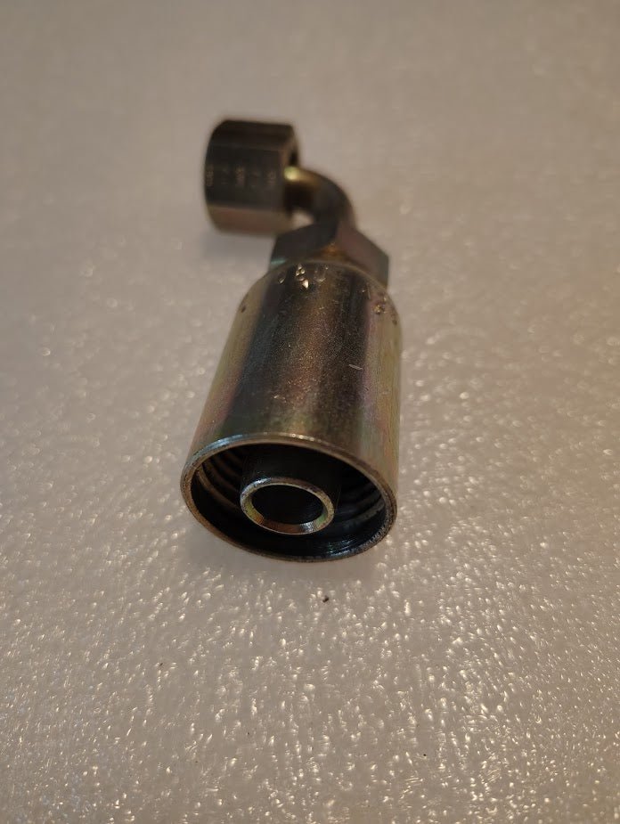 A close-up of a Weatherhead 08U-A26 (1/2 hose x 3/8 ORF female fitting, CS32-8X6) metal hydraulic connector with a hex nut, designed for 100R1 hoses, placed on a textured light-colored surface.