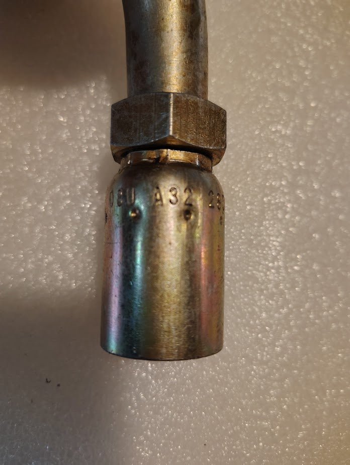 A close-up of a Weatherhead 08U-A32 1/2 Hose x 3/4 ORF Female Fitting (CS32-8X12) with “A32” markings, showing some wear and discoloration against a textured, light-colored background.