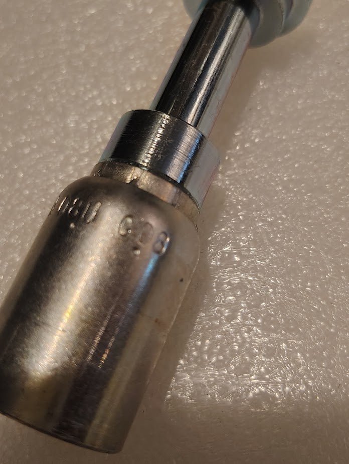 A close-up of a metal socket wrench head marked 6.0 mm sits on a textured white surface, a tool often used for assembling 08U-G08 Weatherhead 1/2 Hose x 1/2 Code 61 Flange Fitting (CS47-8X8) or hydraulic hose connections.