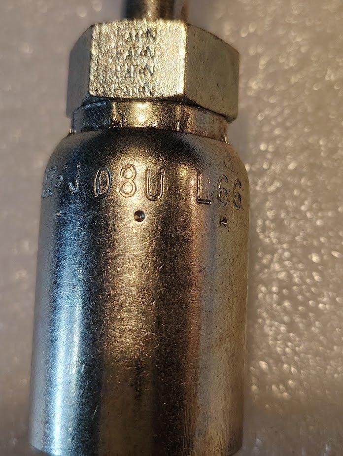 Close-up of a Weatherhead 08U-L66 CS31-8X6 fitting (1/2 hose x 3/8 ORF female), a metallic cylindrical piece engraved 08U L66, shown against a textured, light-toned background.