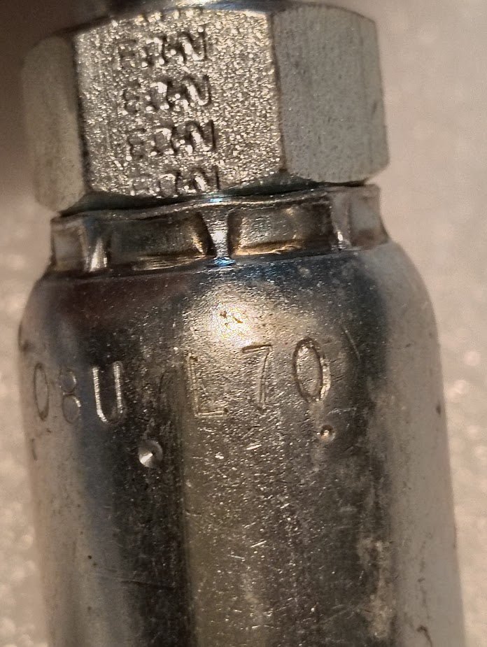 Close-up of a Weatherhead 08U-L70 (1/2 Hose x 5/8 ORF Female Fitting, CS31-8X10) metal pipe fitting with hexagonal nut and engraved markings, including “USA” and “L70.” Slightly worn, typical for hydraulic hose applications.