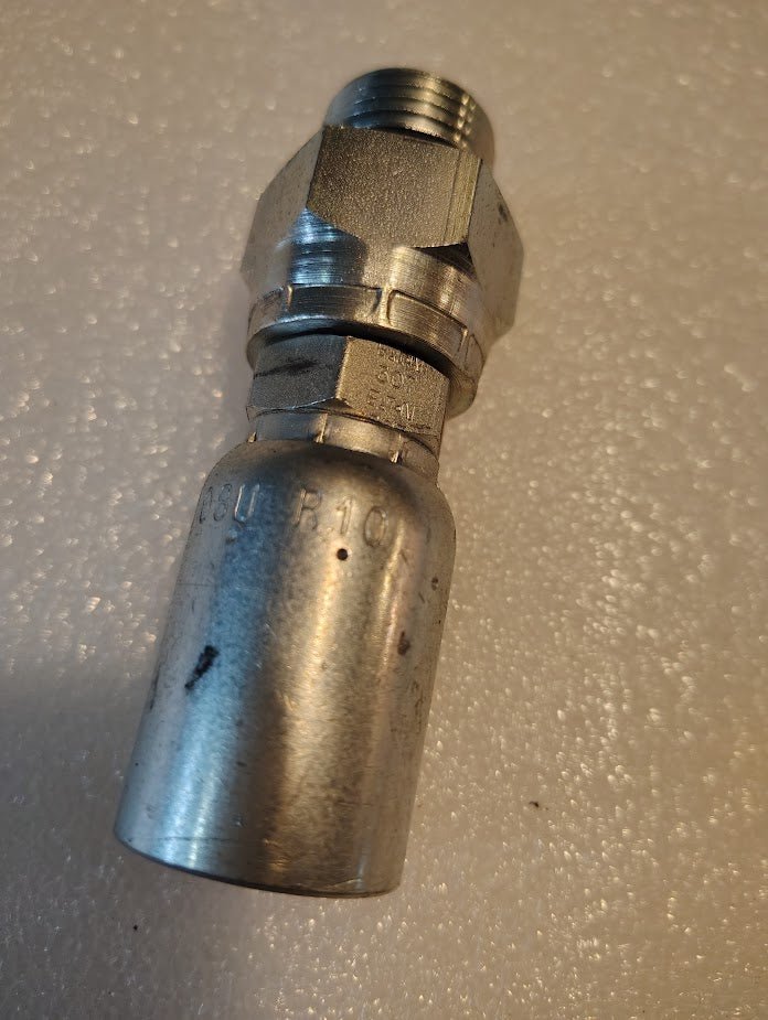 A close-up of the Weatherhead 08U-R10, a 1/2 hose x 5/8 ORB male hydraulic fitting (CS12-8X10), featuring a hexagonal nut and threaded end, made for use with 100R1 hoses, resting on a textured white surface.