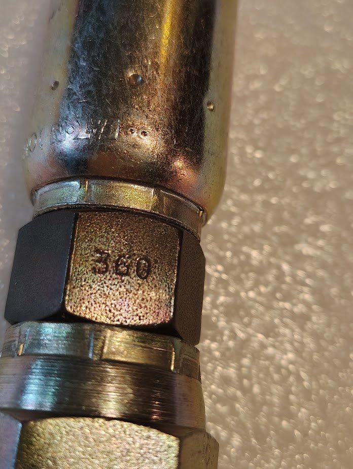 Close-up of a 10U-360 Weatherhead 5/8 Hose x 5/8 BSPP Female Fitting (CS10-10X10) with a hex nut labeled 360, featuring a shiny, reflective finish against a textured light background. Compatible with Weatherhead fittings and hoses.