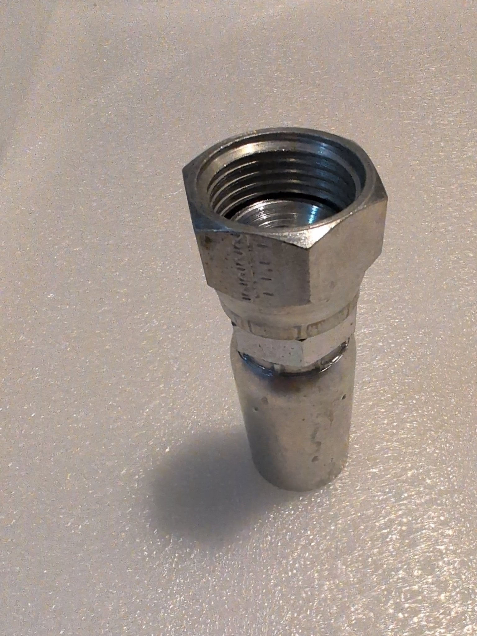 Close-up of a Weatherhead 10U-612 (CS09-10X12) hydraulic fitting, 5/8 hose x 3/4 JIC female, featuring a hexagonal nut and threaded interior, shown upright on a textured white surface.
