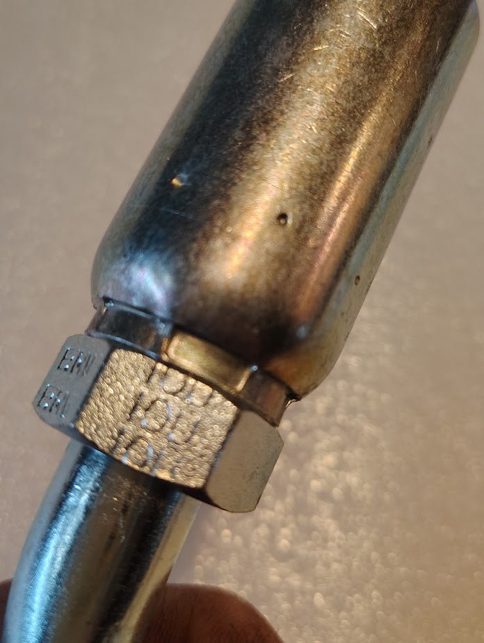 A close-up of the Weatherhead 10U-A70 5/8 Hose x 5/8 ORF Female Fitting (CS33-10X10) showcases its metallic, hexagonal nut design—ideal for hydraulic hose or 100R2 hoses—contrasting with a softly blurred background.