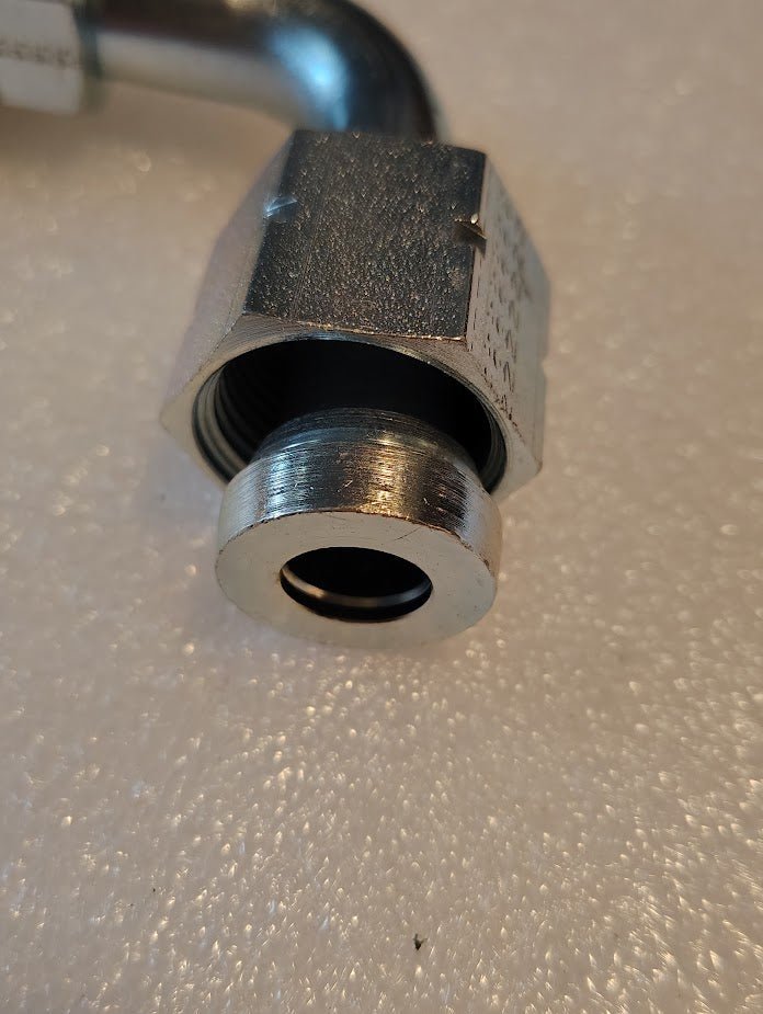Close-up of a Weatherhead 10U-A70 fitting (5/8 hose x 5/8 ORF female, CS33-10X10), metal and threaded, compatible with 100R2 hoses and Weatherhead fittings, on a textured white surface.