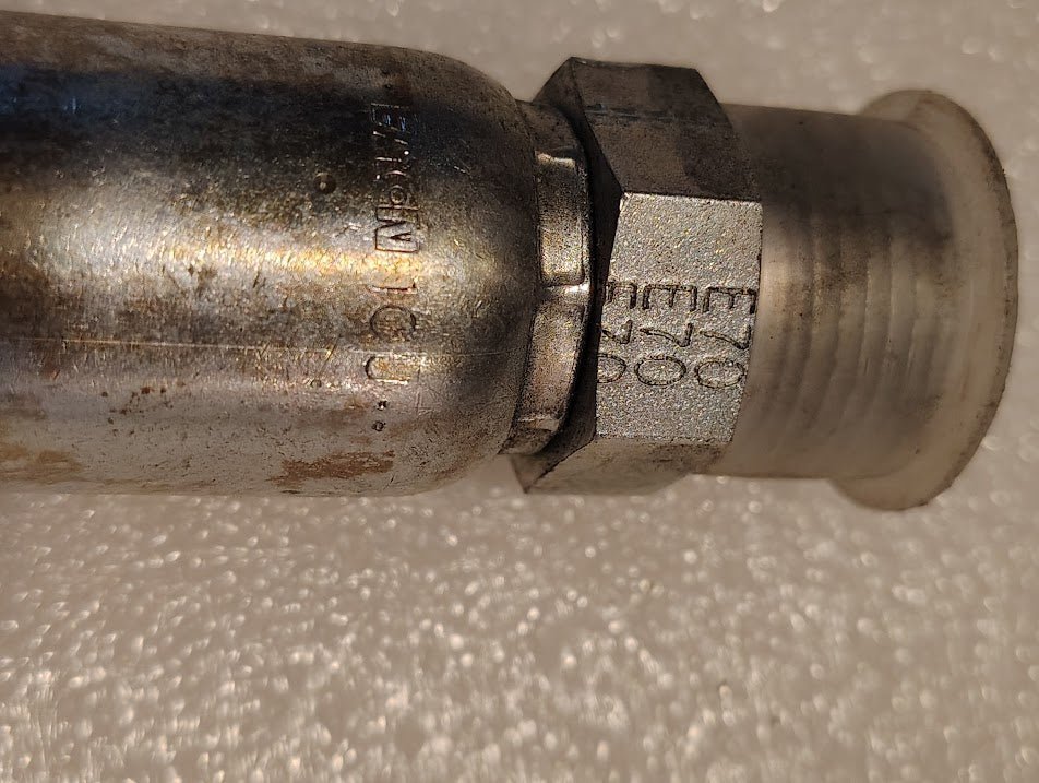 Close-up of a Weatherhead 10U-E70 5/8 Hose x 5/8 ORF Male Fitting (CS29-10X10), showing its hexagonal fitting and engraved markings; the metal surface appears slightly worn and oxidized on a textured white background.