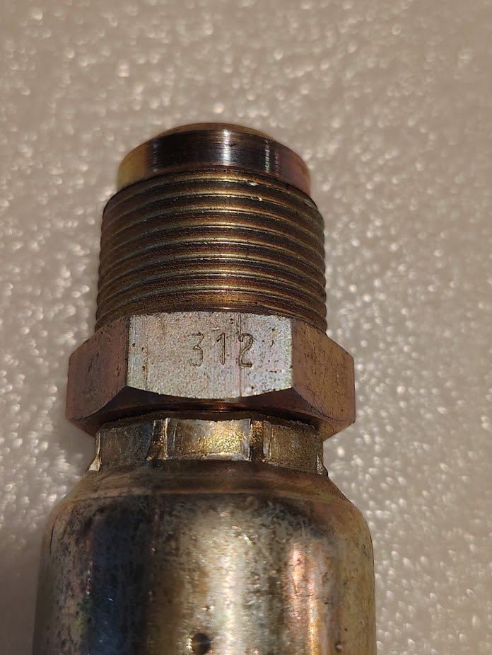 A close-up of the Weatherhead 12U-312 CS06-12X12, a 3/4 Hose x 3/4 SAE male metal fitting marked 312, shown on a textured white surface, commonly used for compatible fittings and hydraulic hose applications.