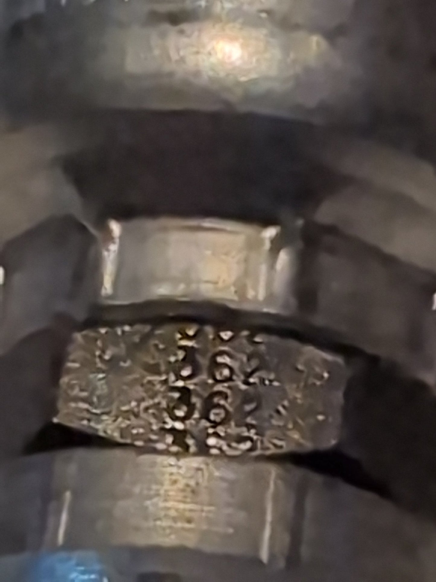 Close-up of a Weatherhead 12U-362 (3/4 Hose x 3/4 BSPP Female Fitting, CS10-12X12) metallic part, engraved with numbers 62 and 36 on a textured surface, surrounded by smooth cylindrical sections typical of hydraulic fittings.