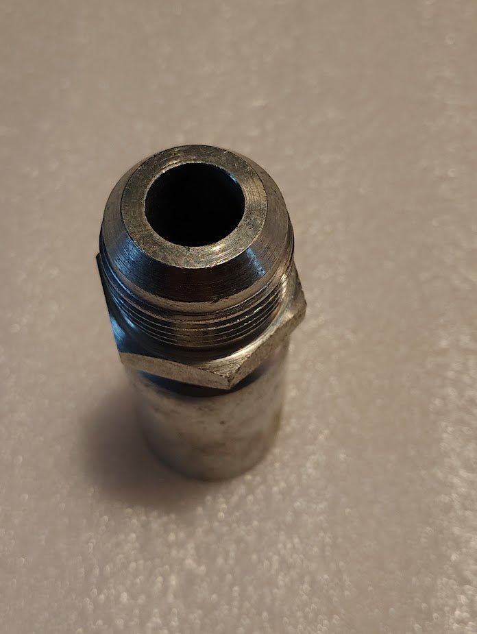 A close-up of the Weatherhead 12U-516, a 3/4 hose x 1 SAE male metal fitting with a hexagonal section, upright on a light-textured surface—ideal for hydraulic hose fittings and compatible with 100R1 hoses.