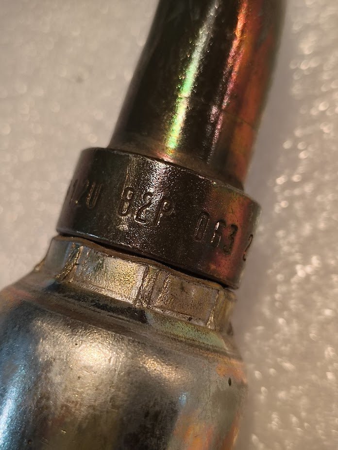 Close-up of a Weatherhead 12U-82P 3/4 Hose x 3/4 BSPP Female Fitting (CS46-12X12), showing engraved markings and numbers on a textured, light-colored background.