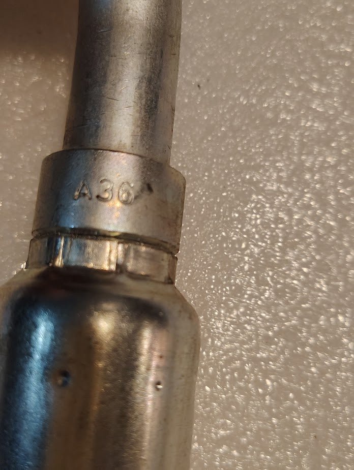 A close-up of a metallic, cylindrical 12U-A36 Weatherhead 3/4 Hose x 1 ORF Female Fitting (CS32-12X16), stamped with A36 near a seam, shown against a textured white background; compatible with Couplamatic and Weatherhead fittings.