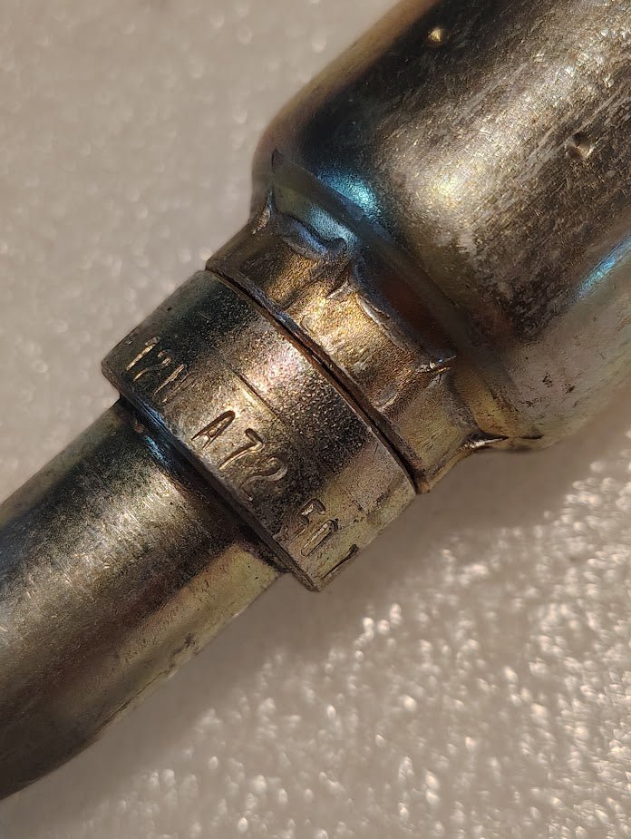Close-up of a metallic item resembling Weatherheads 12U-A72 3/4 Hose x 3/4 ORF Female Fitting with A72 6G1 engraved, featuring indented ridges and a worn metal surface against a textured white background.