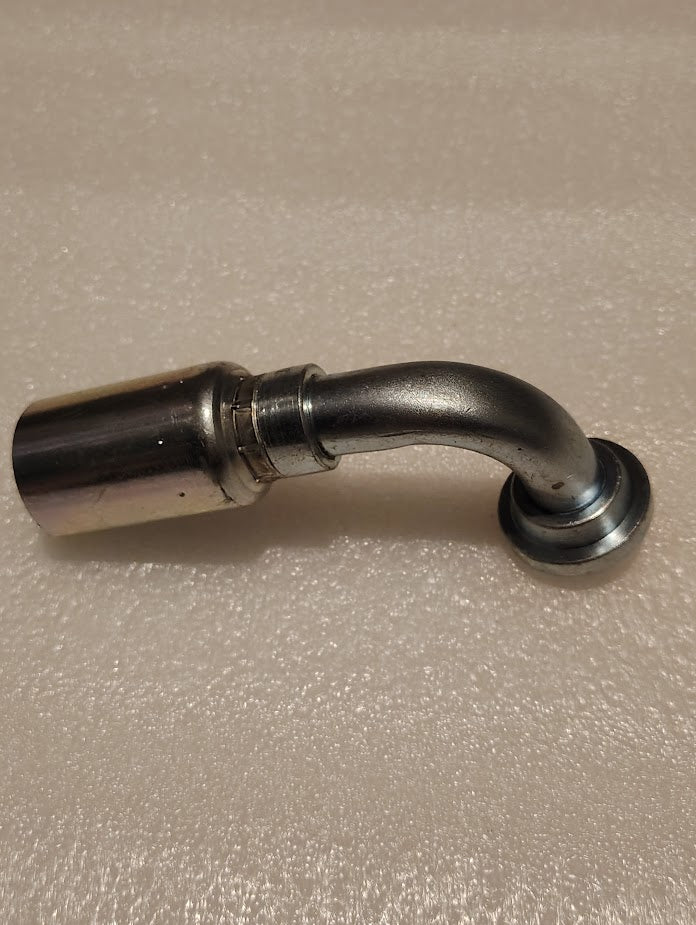 A 12U-G72 Weatherhead 3/4 Hose x 3/4 Code 61 Flange Fitting (CS53-12X12) lies on a textured, light surface, resembling a metal pipe with a curved section and flared end.