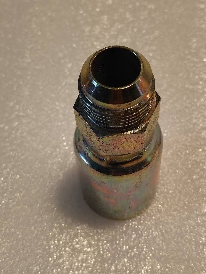 A close-up photo of the Weatherhead 16U-514 fitting, a 1 hose x 7/8 SAE male connector (CS08-16X14), with a threaded hex section and tapered end, shown on a textured, light surface.