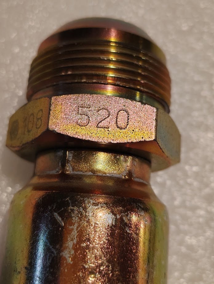 Close-up of a Weatherhead 16U-520 (1 Hose x 1 1/4 JIC Male Fitting, CS08-16X20) metallic fitting with threaded top and hexagonal section marked 708 and 520, featuring an iridescent finish on a white textured background.